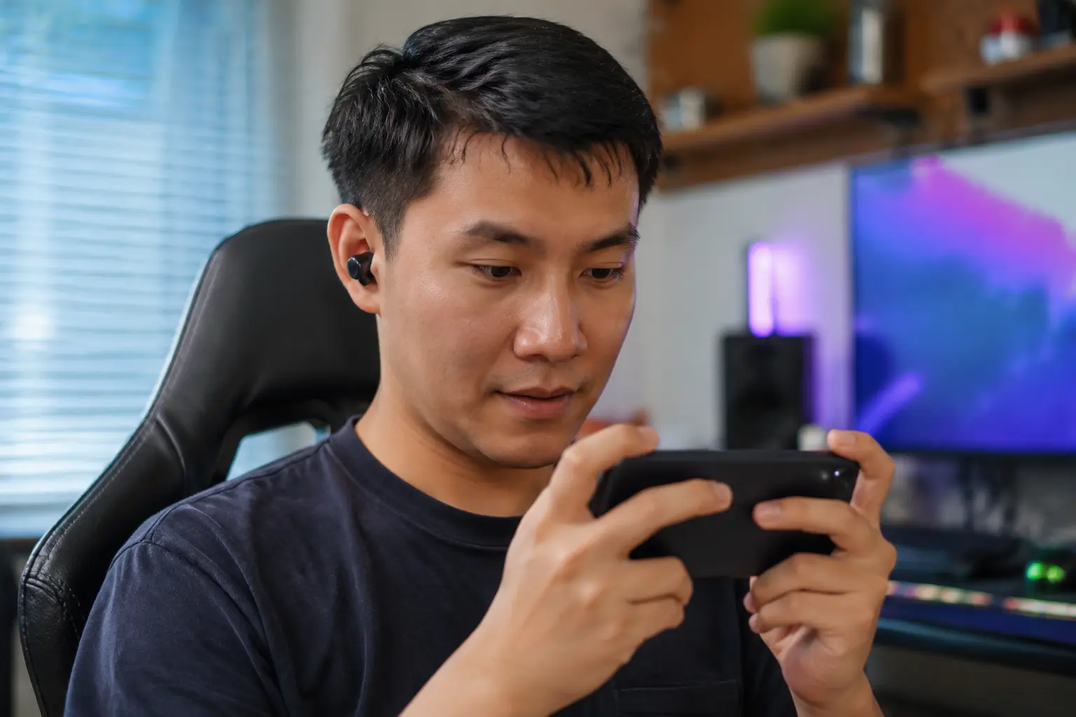 Man playing a mobile game with gaming earbuds