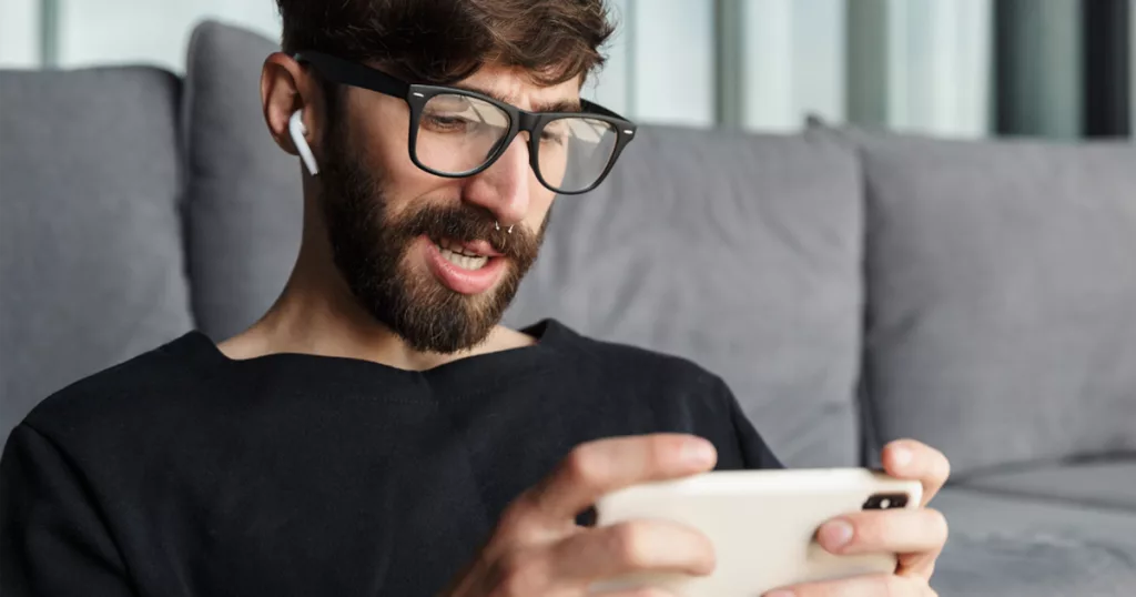 Man playing a mobile game with gaming earbuds
